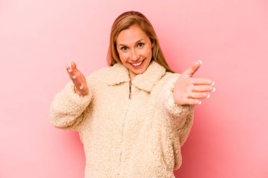 Pembe arka planda izole edilmiş genç beyaz kadın kameraya sarıldığı için kendinden emin..