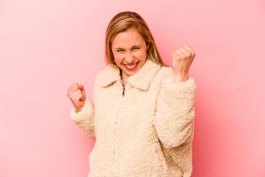 Pembe arka planda soyutlanmış, tasasız ve heyecanlı genç bir beyaz kadın. Zafer konsepti.