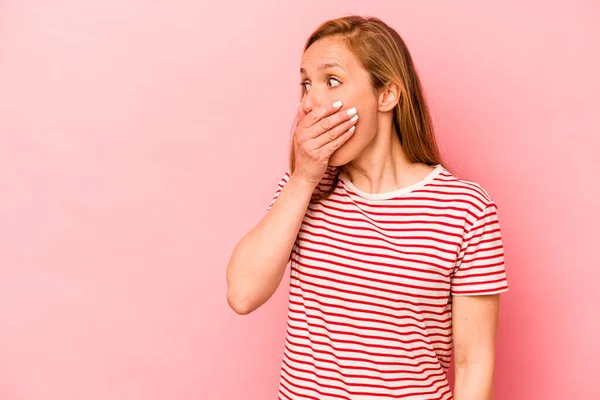 Pembe arka planda izole edilmiş beyaz bir kadın. Düşünceli bir şekilde ağzıyla ağzını kapatan bir fotokopi odasına bakıyor..