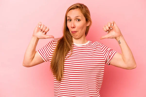 Pembe arka planda izole genç beyaz kadın gururlu ve kendinden emin hissediyor, örnek olarak..