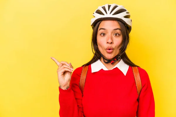 若いです学生ヒスパニック女性身に着けています自転車ヘルメット黄色の背景に隔離された側面を指して — ストック写真