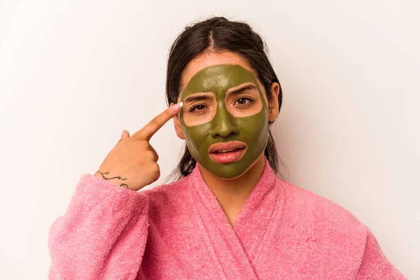 Beyaz arka planda izole edilmiş yüz maskesi takan genç İspanyol kadın işaret parmağıyla yaptığı hayal kırıklığı jestini gösteriyor..