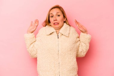 Pembe arka planda izole edilmiş genç beyaz kadın yakın bir tehlike nedeniyle şoka uğruyor.