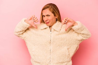 Pembe arka planda izole edilmiş genç beyaz kadın baş parmağını aşağı gösteriyor, hayal kırıklığı konsepti..