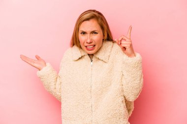 Pembe arka planda izole edilmiş beyaz bir kadın elinde bir ürün tutuyor..