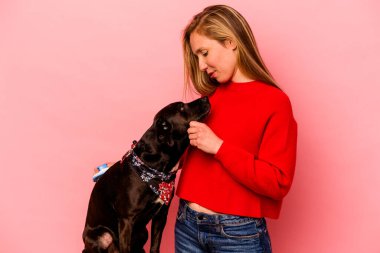 Pembe arka planda köpeği tarayan beyaz bir kadın.