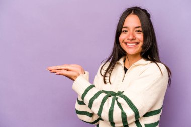 Mor arka planda izole edilmiş genç İspanyol kadın avucunun içinde bir kopya alanı tutuyor..