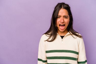 Mor arka planda izole edilmiş genç İspanyol kadın çok kızgın, öfkeli, hayal kırıklığına uğramış.