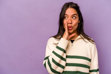 Mor arka planda izole edilmiş genç İspanyol kadın gizli bir sıcak fren haberi veriyor ve yan bakıyor.