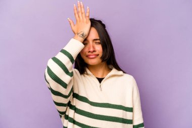 Mor arka planda izole edilmiş genç İspanyol kadın bir şeyi unutuyor. Alnına avuç içi ile vuruyor ve gözlerini kapıyor..