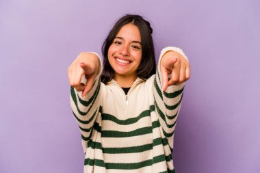Mor arka planda izole edilmiş genç İspanyol kadın. Önü işaret eden neşeli gülümsemeler..