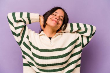 Mor arka planda soyutlanmış genç İspanyol bir kadın kendini güvende hissediyor, elleri başının arkasında..