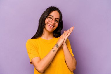 Mor arka planda izole edilmiş genç İspanyol kadın enerjik ve rahat hissediyor, ellerini ovuşturuyor..