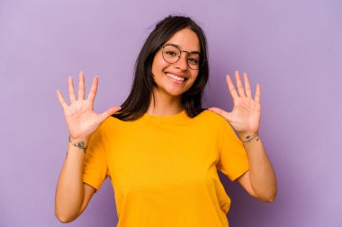Mor arka planda izole edilmiş genç İspanyol kadın on numarayı elleriyle gösteriyor..