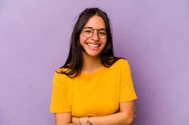 Mor arka planda izole edilmiş genç İspanyol kadın gülüyor ve eğleniyor..