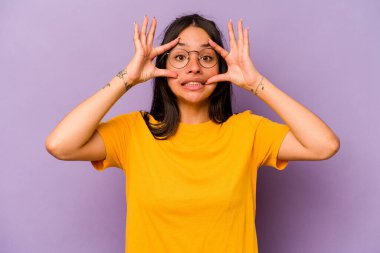 Mor arka planda izole edilmiş genç İspanyol kadın başarı fırsatı bulmak için gözlerini açık tutuyor..