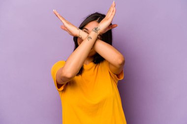 Mor arka planda izole edilmiş genç İspanyol kadın iki kolu çapraz tutuyor, inkar kavramı.