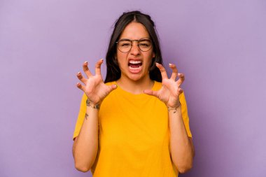 Mor arka planda izole edilmiş genç İspanyol kadın pençelerini bir kediyi taklit ederken gösteriyor, agresif bir hareket..