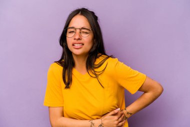 Mor arka planda karaciğer ağrısı çeken, karnı ağrıyan genç bir İspanyol kadın..