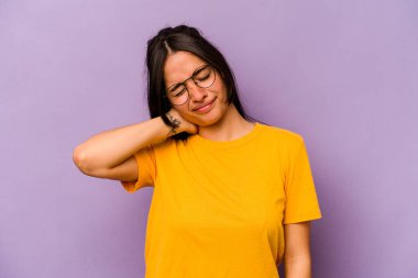 Mor arka planda izole edilmiş genç İspanyol kadın stresten dolayı boynu ağrıyor, masaj yapıyor ve elle dokunuyor..