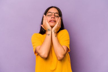 Mor arka planda izole edilmiş genç İspanyol kadın ağlıyor, bir şeyden memnun değil, acı ve kafa karışıklığı konsepti..