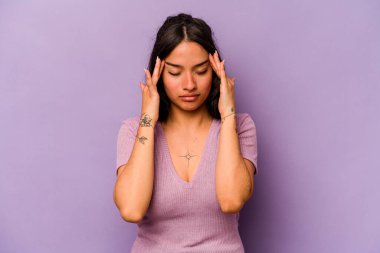 Mor arka planda izole edilmiş genç İspanyol kadın şakaklara dokunuyor ve baş ağrısı çekiyor..