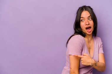 Genç İspanyol kadın mor arka planda izole edilmiş başparmak uzakta, gülüyor ve kaygısız.