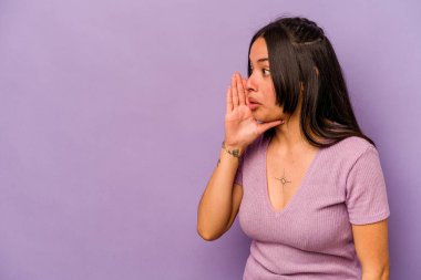 Mor arka planda izole edilmiş genç İspanyol kadın gizli bir sıcak fren haberi veriyor ve yan bakıyor.