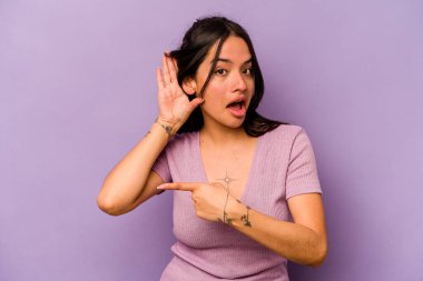 Mor arka planda izole edilmiş genç İspanyol kadın bir dedikoduyu dinlemeye çalışıyor..
