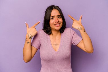 Mor arka planda izole edilmiş genç İspanyol kadın işaret parmağıyla bir hayal kırıklığı gösteriyor..