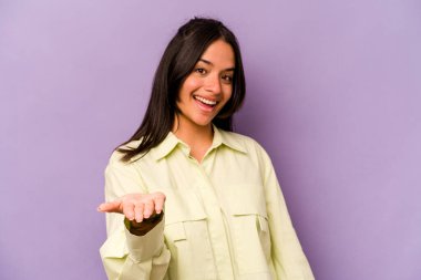 Mor arka planda izole edilmiş genç İspanyol kadın selamlama jesti olarak kameraya elini uzatıyor..