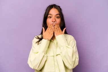 Mor arka planda izole edilmiş genç İspanyol kadın elleriyle ağzını kapatırken şok oldu..