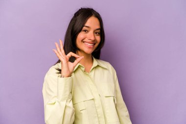 Mor arka planda izole edilmiş genç İspanyol kadın neşeli ve kendinden emin, iyi bir hareket gösteriyor..