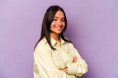 Mor arka planda kendini güvende hisseden, kararlılıkla kollarını kavuşturan genç İspanyol kadın..