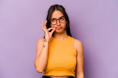 Mor arka planda izole edilmiş genç İspanyol kadın parmakları dudaklarında bir sır saklıyor..