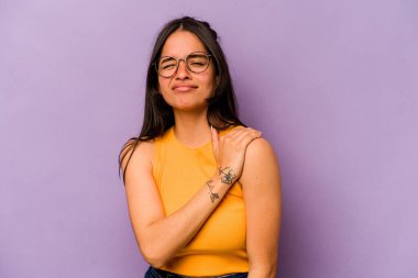 Mor arka planda izole edilmiş genç İspanyol kadın omuz ağrısı çekiyor..