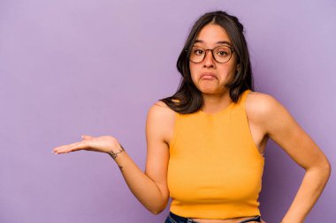Mor arka planda izole edilmiş genç İspanyol kadın bir avuç içinde fotokopi alanı ve belinde bir el daha gösteriyor..