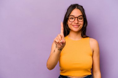 Mor arka planda izole edilmiş genç İspanyol kadın bir numarayı parmağıyla gösteriyor..