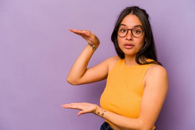 Mor arka planda izole edilmiş genç İspanyol kadın elleri arasında bir kopya alanı tutarken şok ve hayrete düştü..