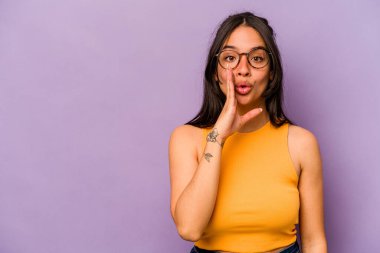 Mor arka planda izole edilmiş genç İspanyol kadın gizli bir sıcak fren haberi veriyor ve yan bakıyor.