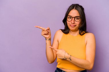 Mor arka planda izole edilmiş genç İspanyol kadın işaret parmağıyla bir fotokopi alanını işaret ederek şok oldu..
