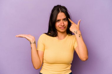 Mor arka planda izole edilmiş genç İspanyol kadın işaret parmağıyla bir hayal kırıklığı gösteriyor..