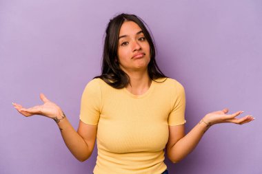 Mor arka planda izole edilmiş genç İspanyol kadın sorgulama sırasında omuz silkiyor ve şüphe duyuyor..