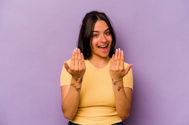 Mor arka planda izole edilmiş genç İspanyol kadın sanki seni davet ediyormuş gibi seni işaret ediyor..