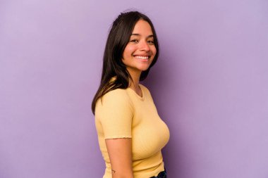 Mor arka planda izole edilmiş genç İspanyol kadın ellerini kalçasından ayırmıyor..