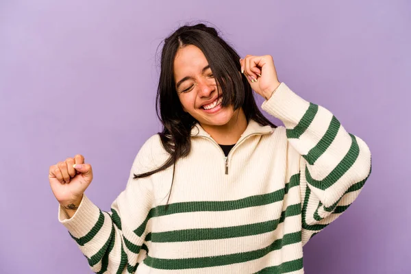 Genç İspanyol kadın mor arka planda izole edilmiş dans ediyor ve eğleniyor..