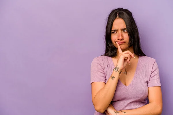 Jonge Spaanse Vrouw Geïsoleerd Paarse Achtergrond Kijken Zijwaarts Met Twijfelachtige — Stockfoto