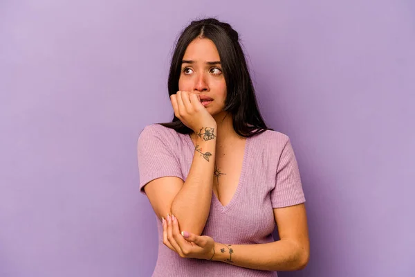 紫の背景に爪をかむ若いヒスパニック系の女性 神経と非常に不安 — ストック写真