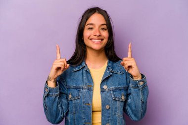 Mor arka planda izole edilmiş genç İspanyol kadın iki parmağı da boş bir alan gösteriyor..