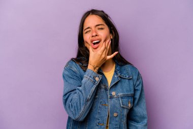 Mor arka planda izole edilmiş genç İspanyol kadın güçlü bir diş ağrısı, azı dişi ağrısı var..